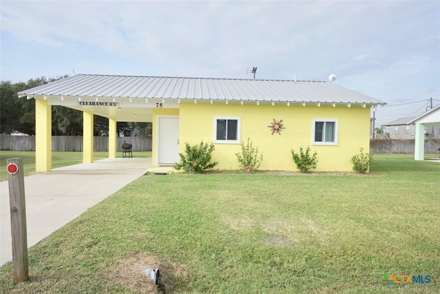 view of front of house with an attached carport, fence, a front yard, and metal roof