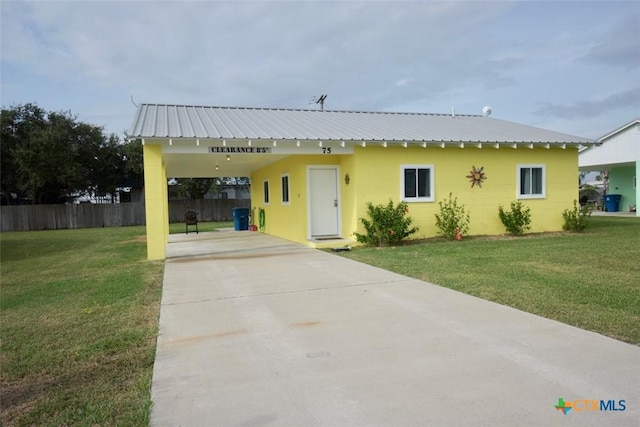 view of front of home featuring an attached carport, concrete block siding, a front yard, and metal roof