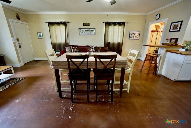 dining room featuring concrete block wall, concrete floors, ceiling fan, and ornamental molding