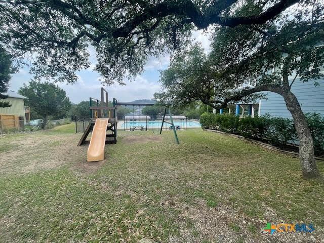view of playground with a lawn and a fenced in pool