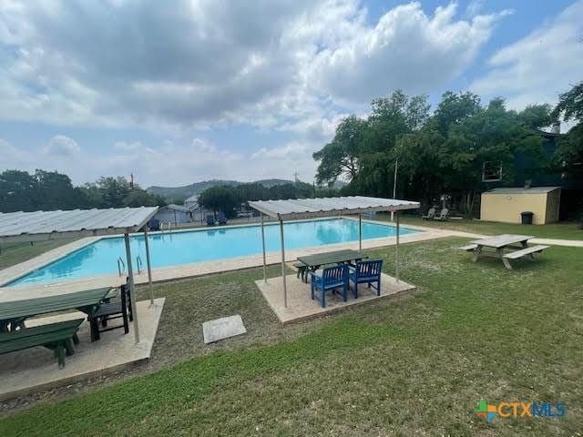 community pool featuring a yard, an outdoor structure, a shed, and a patio area
