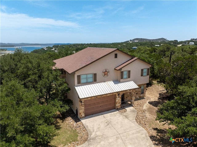 1350 Colleen Dr, Canyon Lake, TX 78133 - view of front of house with stone siding, concrete driveway, an attached garage, and a water view