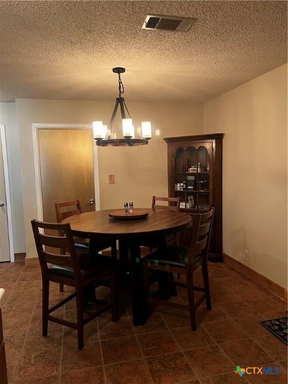dining room with a chandelier, a textured ceiling, and visible vents