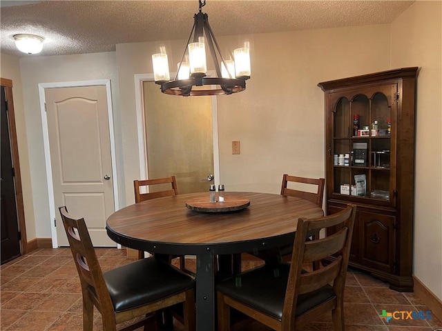 dining room featuring baseboards, a chandelier, and a textured ceiling