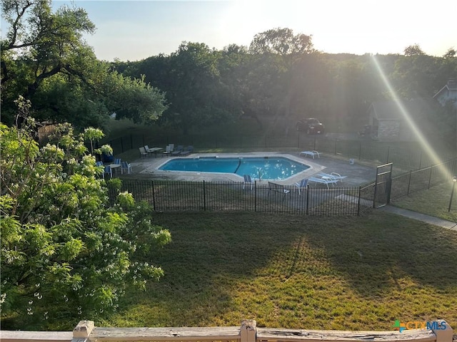 pool featuring a lawn, a patio, and fence