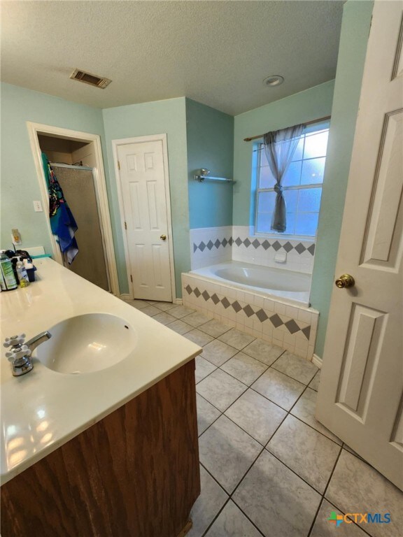 2006 Indian Camp Trl, Copperas Cove, TX 76522 - full bathroom featuring tile patterned flooring, a textured ceiling, a bath, vanity, and a shower with shower door