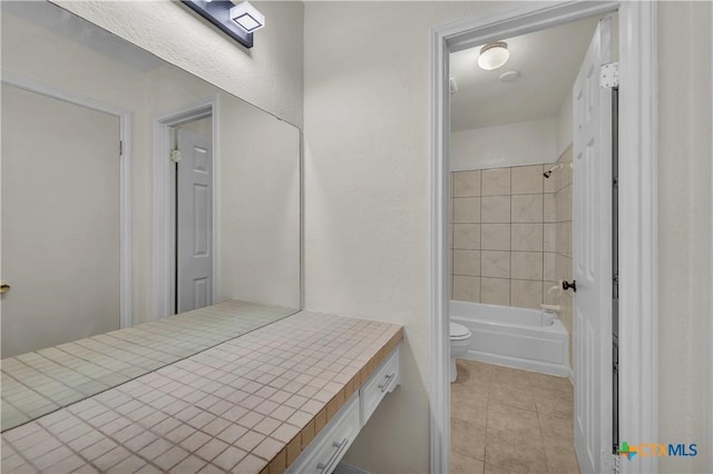 bathroom featuring toilet, tiled shower / bath combo, and tile patterned flooring