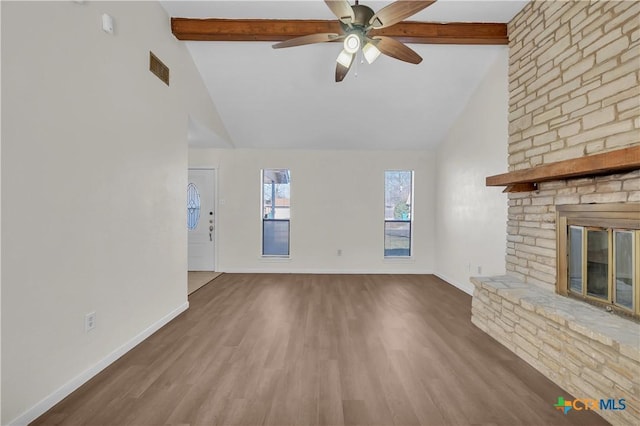 unfurnished living room with ceiling fan, hardwood / wood-style floors, a fireplace, and lofted ceiling with beams