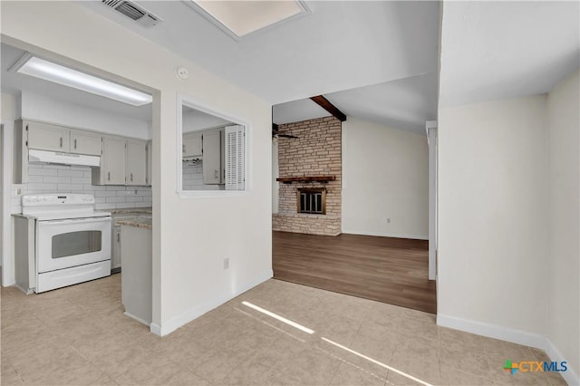 kitchen featuring white electric range oven, tasteful backsplash, lofted ceiling with beams, light tile patterned flooring, and a brick fireplace