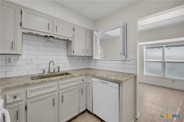 kitchen featuring white dishwasher, sink, tasteful backsplash, white cabinetry, and light tile patterned flooring