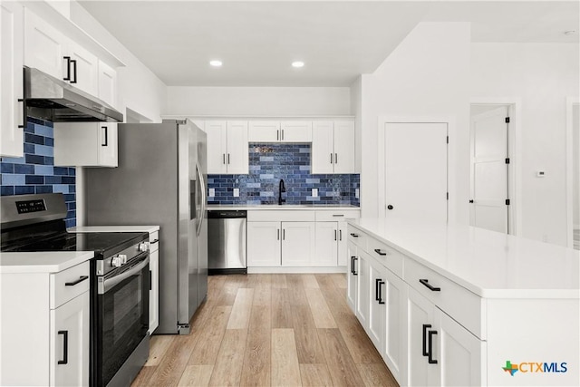 324 Idaho St, San Antonio, TX 78203 - kitchen with stainless steel appliances, under cabinet range hood, a sink, light wood finished floors, and white cabinetry