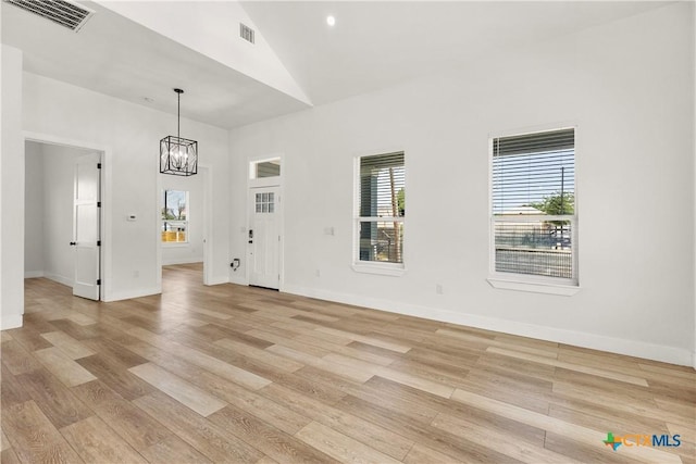 324 Idaho St, San Antonio, TX 78203 - unfurnished dining area with light wood-type flooring, a chandelier, high vaulted ceiling, and baseboards