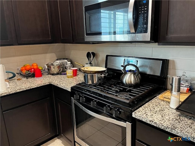 1157 Esplanade Pkwy, San Marcos, TX 78666 - kitchen with stainless steel appliances, decorative backsplash, dark brown cabinetry, and light stone countertops