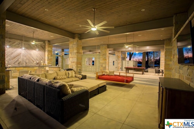 interior space featuring wooden ceiling, beamed ceiling, ceiling fan, light tile patterned floors, and ornate columns