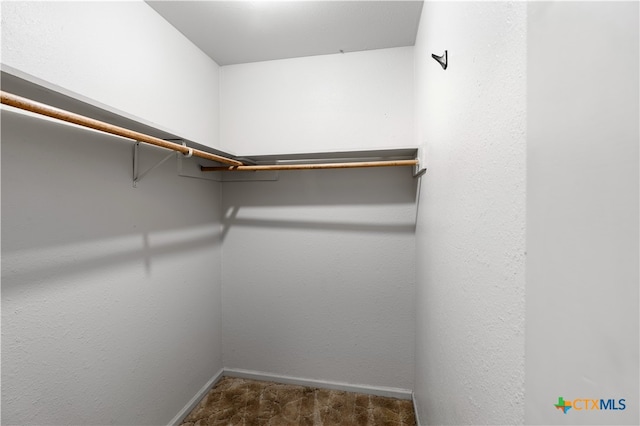 walk in closet featuring dark colored carpet