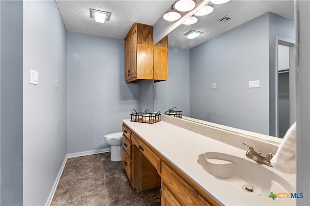 bathroom with vanity, a textured ceiling, and toilet