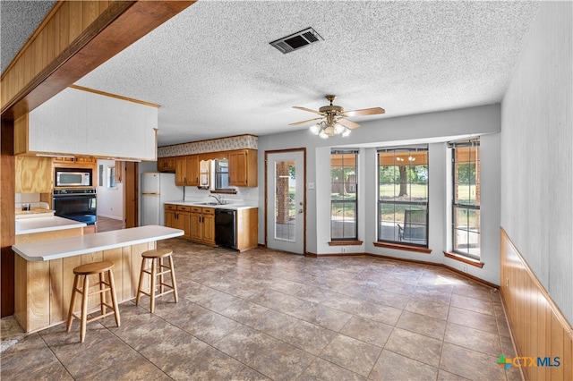 kitchen with a kitchen breakfast bar, a textured ceiling, and black appliances