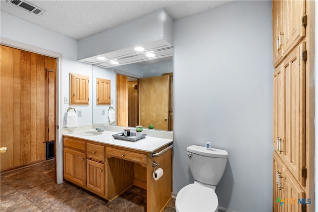 bathroom with toilet, vanity, and a textured ceiling