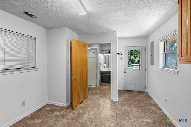 interior space with connected bathroom, a textured ceiling, tile patterned floors, and ceiling fan