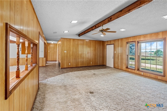 unfurnished living room featuring lofted ceiling with beams, wooden walls, a textured ceiling, and ceiling fan