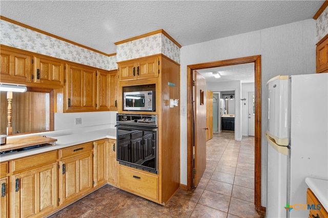 kitchen with dark tile patterned flooring, black appliances, a textured ceiling, and crown molding