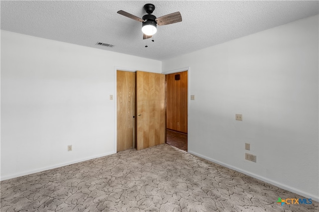 carpeted spare room with a textured ceiling and ceiling fan