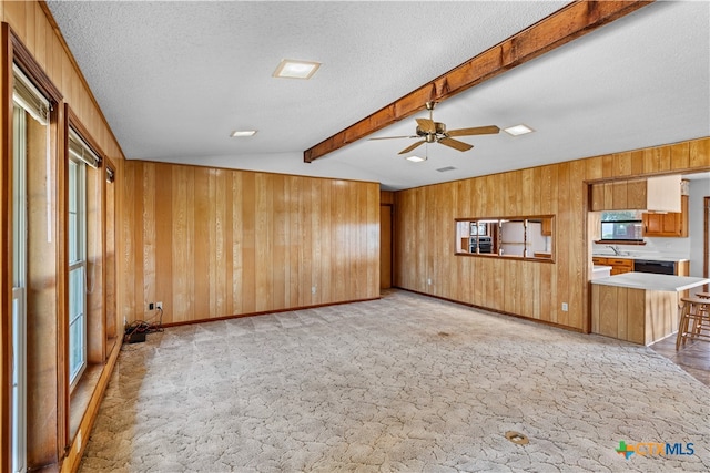 unfurnished living room featuring vaulted ceiling with beams, wood walls, a textured ceiling, and ceiling fan