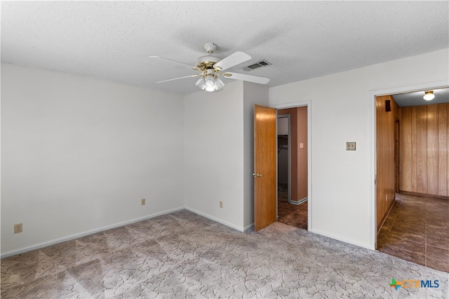 spare room featuring a textured ceiling, light colored carpet, and ceiling fan