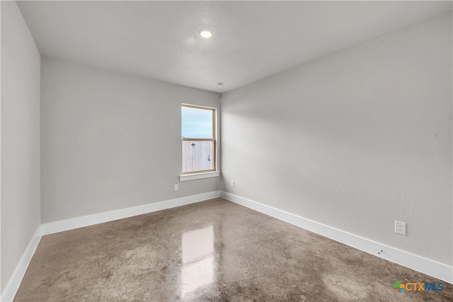 empty room featuring finished concrete flooring and baseboards