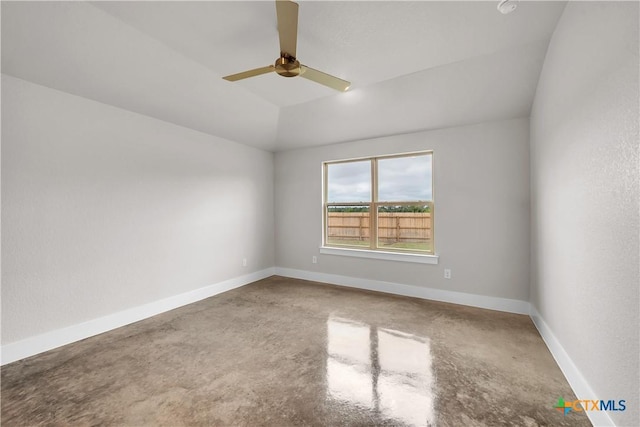 empty room with lofted ceiling, concrete flooring, a ceiling fan, and baseboards