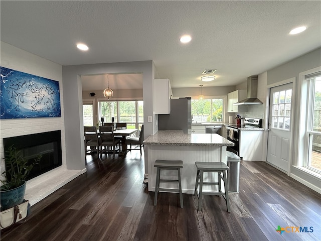 107 Savannah Dr, Victoria, TX 77904 - kitchen with appliances with stainless steel finishes, wall chimney range hood, white cabinets, dark wood-type flooring, and hanging light fixtures