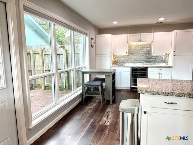 107 Savannah Dr, Victoria, TX 77904 - kitchen with wine cooler, white cabinetry, dark wood-type flooring, backsplash, and light stone countertops