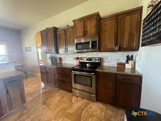 5618 County Road 3300, Kempner, TX 76539 - kitchen with appliances with stainless steel finishes, decorative backsplash, arched walkways, and dark stone countertops