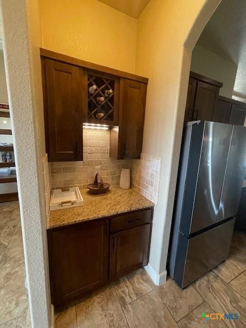 5618 County Road 3300, Kempner, TX 76539 - kitchen with freestanding refrigerator, decorative backsplash, arched walkways, and light stone counters