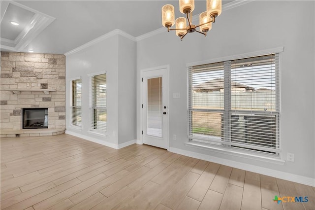 unfurnished living room with a notable chandelier, a stone fireplace, ornamental molding, and light hardwood / wood-style flooring