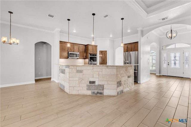 kitchen featuring an inviting chandelier, appliances with stainless steel finishes, crown molding, and decorative light fixtures