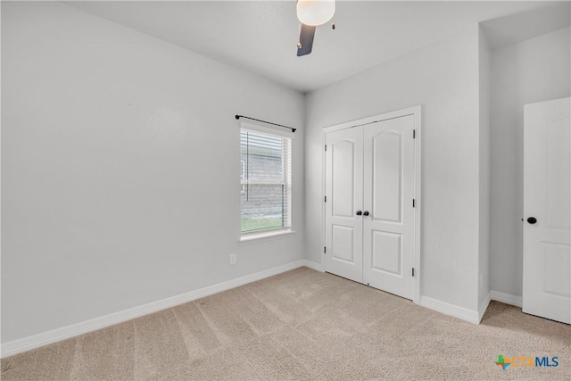 unfurnished bedroom with ceiling fan, light carpet, and a closet