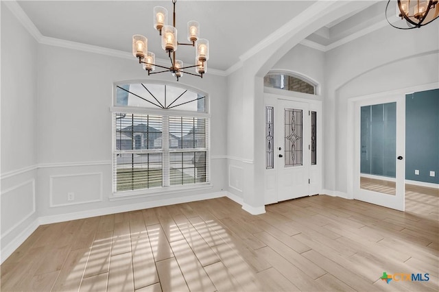 entrance foyer featuring french doors, an inviting chandelier, ornamental molding, and hardwood / wood-style floors