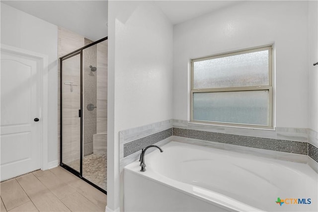 bathroom featuring separate shower and tub and a healthy amount of sunlight