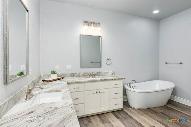 bathroom with vanity, a bath, and wood-type flooring