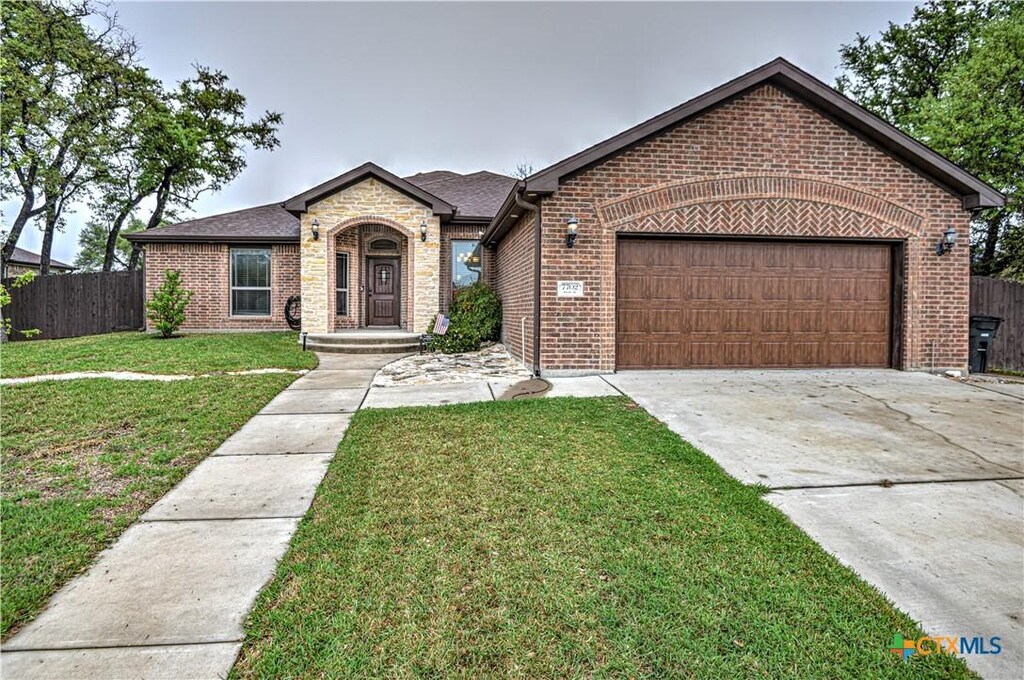 7702 Pyrite Dr, Killeen, TX 76542 - view of front of home with fence, a garage, concrete driveway, a front yard, and brick siding