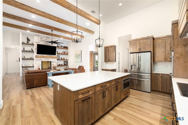7817 W Fm 487, Florence, TX 76527 - kitchen with light wood finished floors, a center island, ceiling fan with notable chandelier, stainless steel appliances, and a fireplace