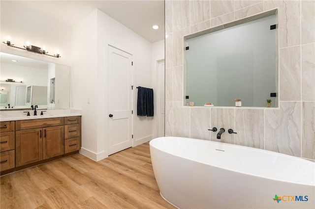 7817 W Fm 487, Florence, TX 76527 - full bathroom with vanity, a soaking tub, tile walls, and wood finished floors