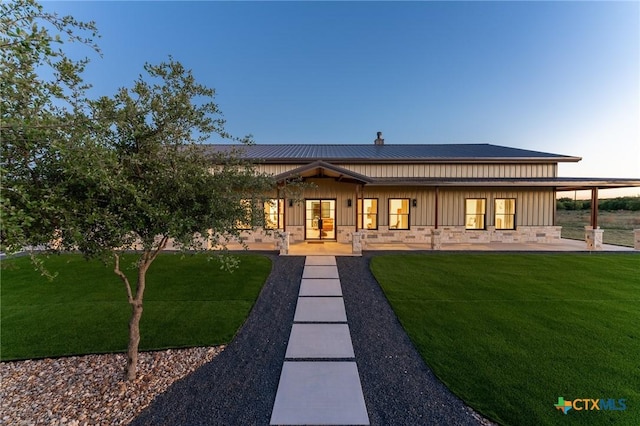 7817 W Fm 487, Florence, TX 76527 - back of property at dusk with stone siding, board and batten siding, a yard, and metal roof