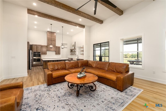 7817 W Fm 487, Florence, TX 76527 - living area featuring beam ceiling, a towering ceiling, light wood-type flooring, a ceiling fan, and baseboards