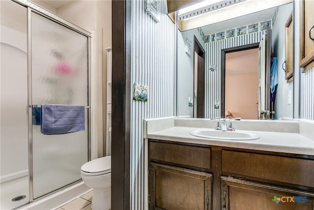 bathroom featuring a shower with door, vanity, tile patterned floors, and toilet