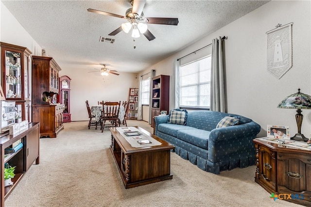 carpeted living room featuring a textured ceiling and ceiling fan