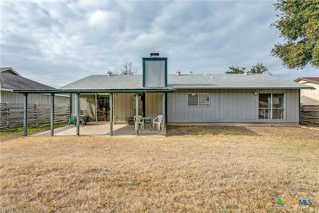 back of house with a lawn and a patio