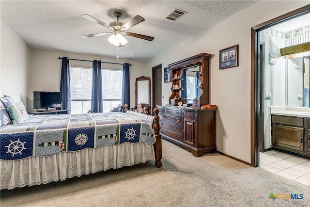 carpeted bedroom with ensuite bathroom, ceiling fan, and a textured ceiling