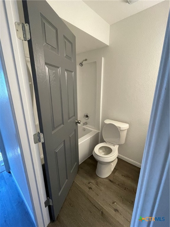 bathroom with hardwood / wood-style flooring, toilet, and tub / shower combination